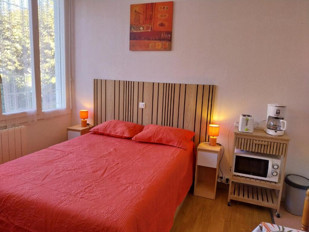 a bedroom with a red bed and a tv at Appartement Sauges 16 in Cazaubon