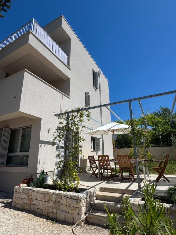 a house with chairs and a table in front of it at Supetar Cypress House - near the beach in Supetar