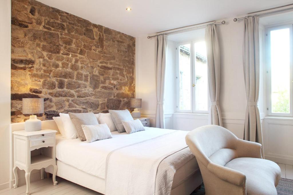 a bedroom with a white bed and a brick wall at Chambres Aux Sabots Rouges in Guéméné-sur-Scorff