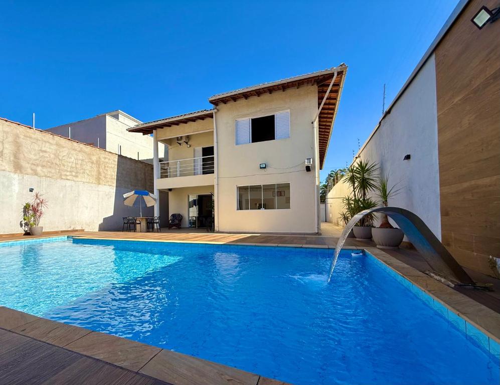 a swimming pool with a water slide in front of a house at Casa virgínia enseada in Guarujá