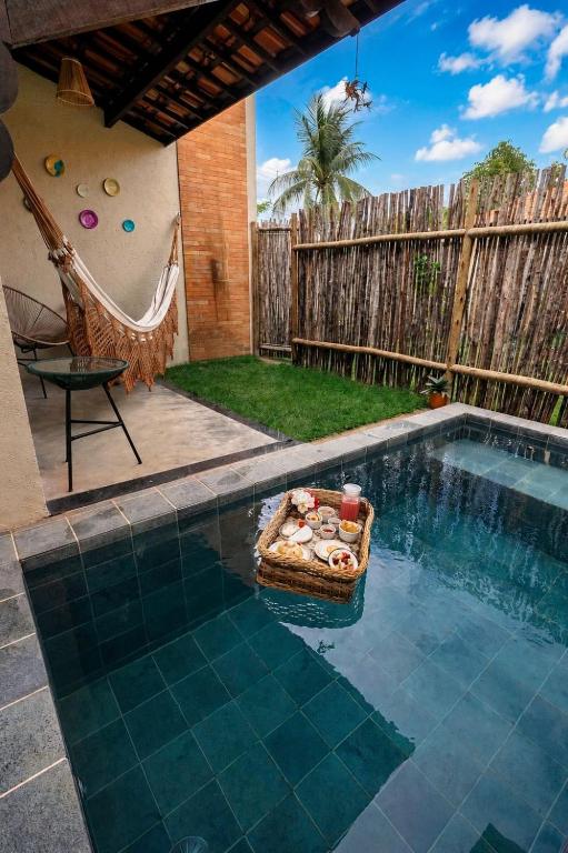 a pool with a chair and a hammock in a backyard at VILA GAHERI Pousada Boutique com Piscina Privativa in São Miguel dos Milagres