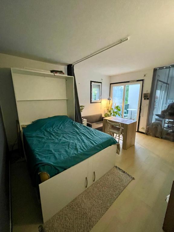 a bedroom with a bed with a green blanket on it at Studio cosy proche bordeaux avec balcon in Villenave-dʼOrnon