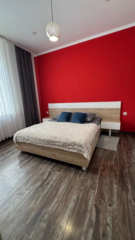 a bedroom with a bed with a red wall at Central Square Apartment in Ternopil