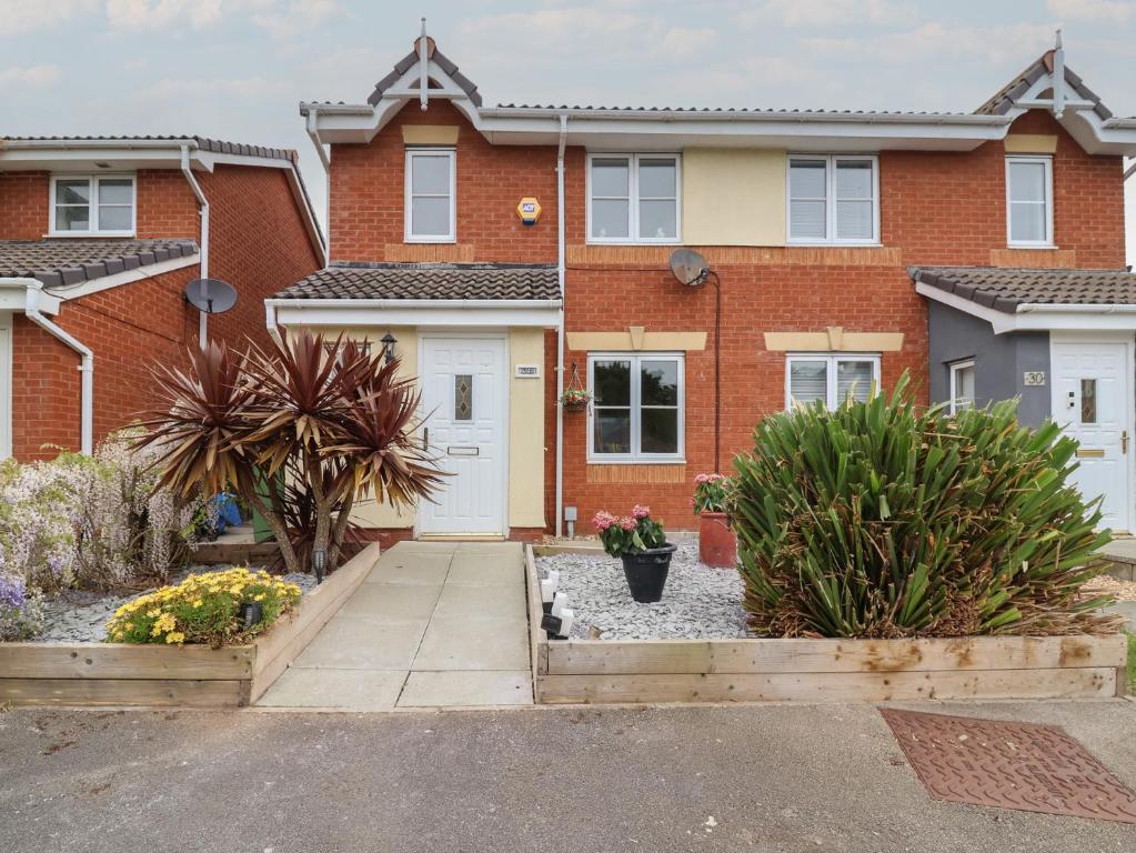 a red brick house with white doors and plants at 31 Llys Ogwen in Prestatyn