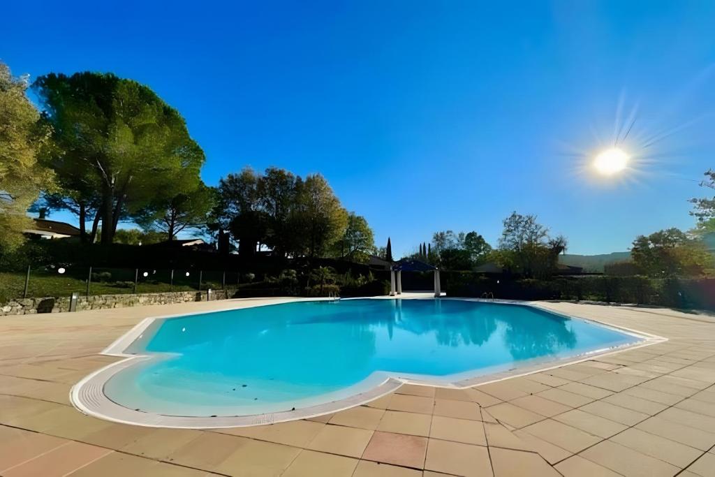 a large swimming pool with blue water in a yard at La Petite Provence in Tourrettes