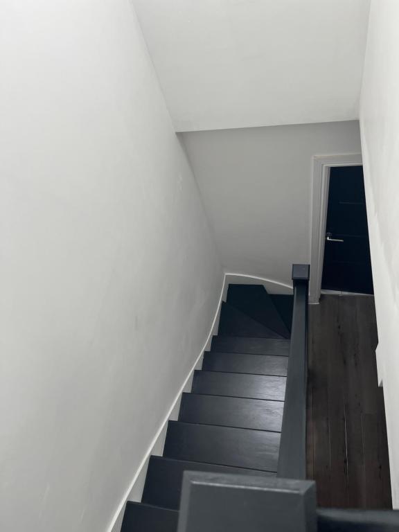 a staircase in a room with white walls and wooden floors at Deluxe family room in Chessington