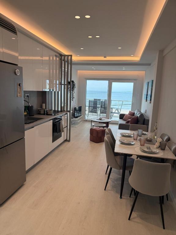 a kitchen and a living room with a table and chairs at Sea View Luxury Apartment Beachfront 3BR in Agia Triada