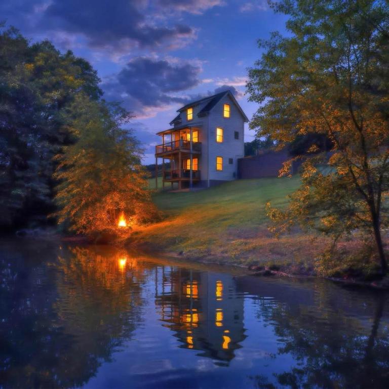 a house on a hill next to a river at night at Riverfront Fishing, Firepit, Only 4 Miles to the Speedway in Bluff City