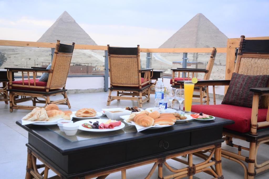 a table with food on it with pyramids in the background at Egypt Aziz pyramids in Cairo