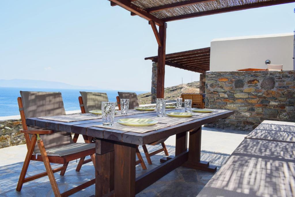 a wooden table on a patio with the ocean in the background at Delta Villa's Kythnos II in Kithnos