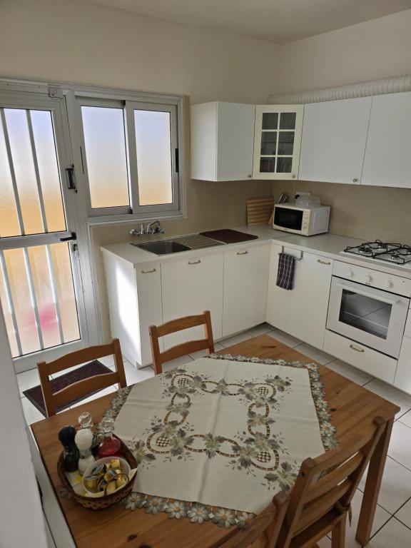 a kitchen with a table and chairs and a kitchen with white cabinets at Indie little house in Limassol