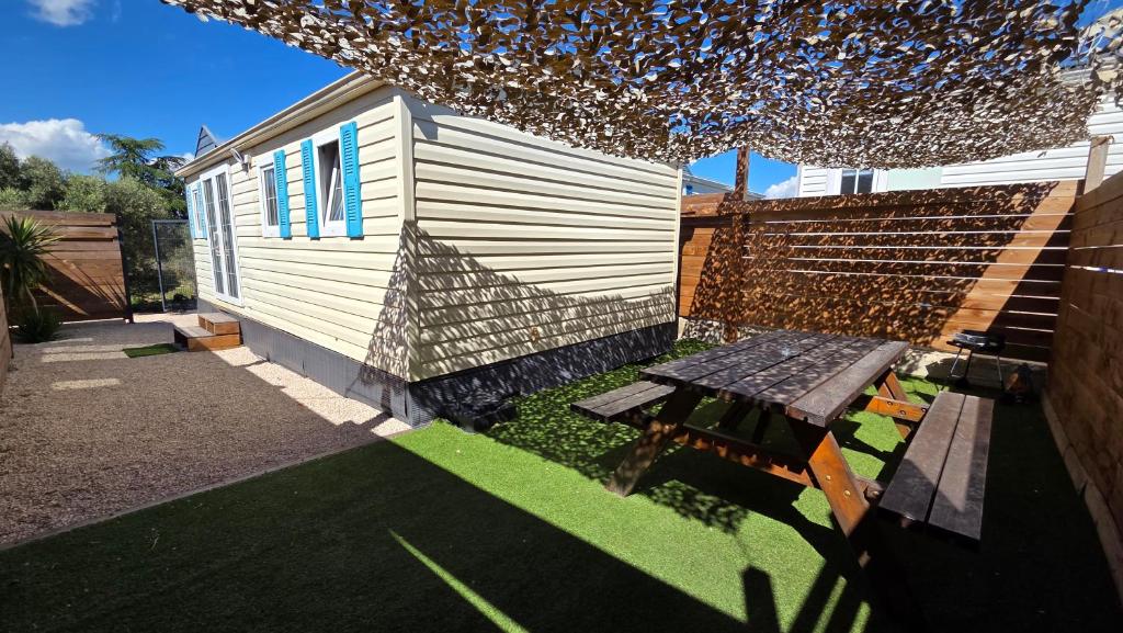a backyard with a bench and a building at Bungalow entre oliviers et pins, -10mn de la plage in Châteauneuf-lès-Martigues
