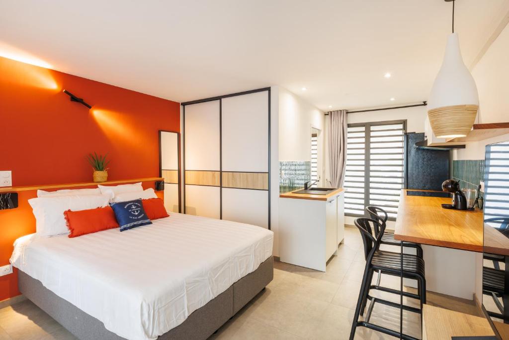 a bedroom with orange walls and a bed and a kitchen at La Kaz Amiral in Saint-Pierre