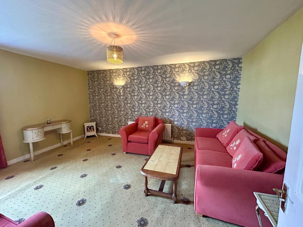 a living room with a pink couch and two chairs at An Teach Ban in Tralee