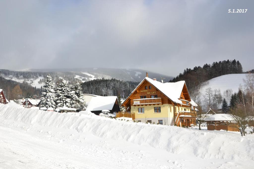 uma casa coberta de neve numa colina cheia de neve em Apartmány Ski Lift em Rokytnice nad Jizerou