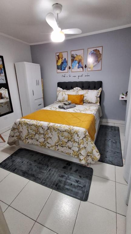 a bedroom with a large bed with a yellow blanket at Minicasa Show! in Jandira