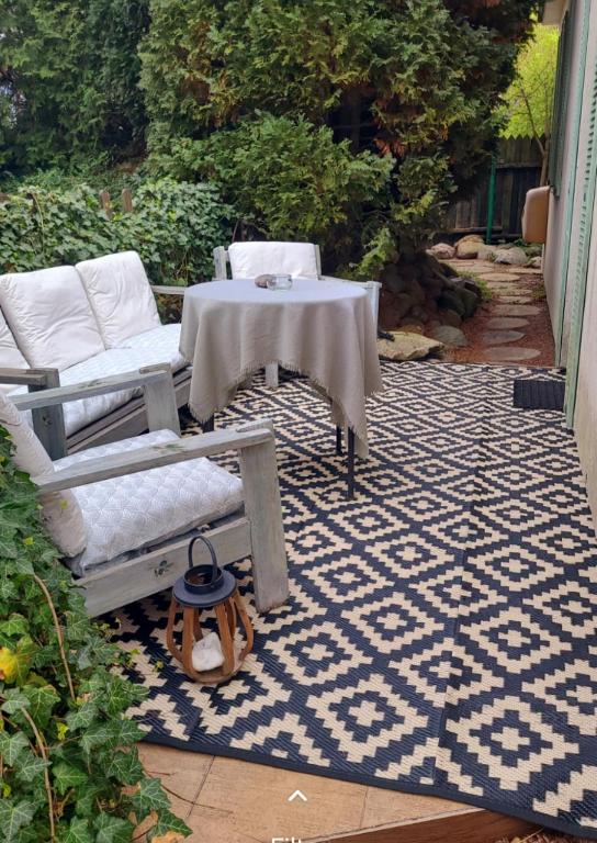 a patio with a table and chairs on a rug at Apartament Szpilka - domek in Police