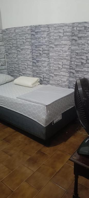 a bed in a room with a brick wall at pousada popular in Barreiras