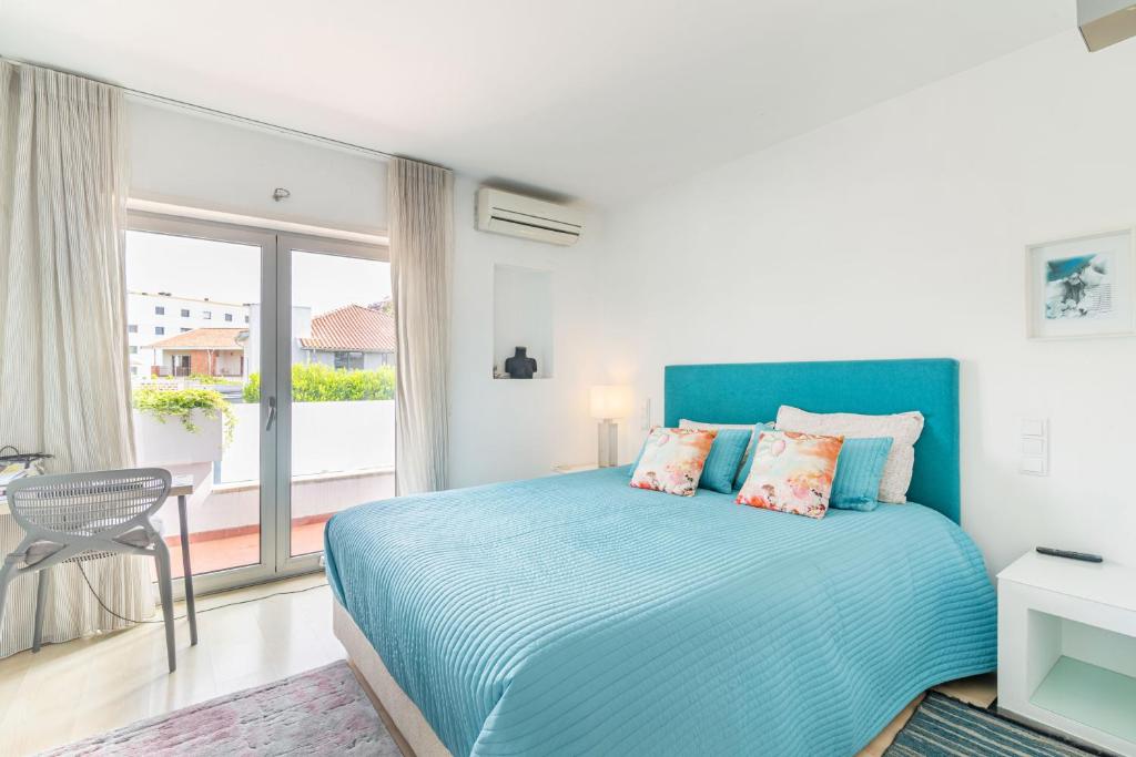 a bedroom with a blue bed and a balcony at Host In Olivença in Vila Nova de Famalicão