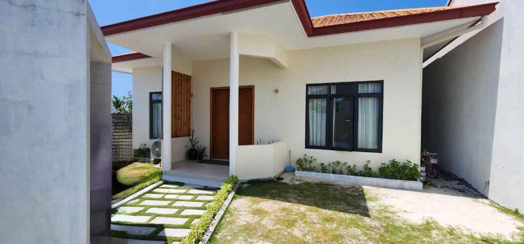 a white house with a pathway in front of it at Anona Beachfront Villa in Filadu