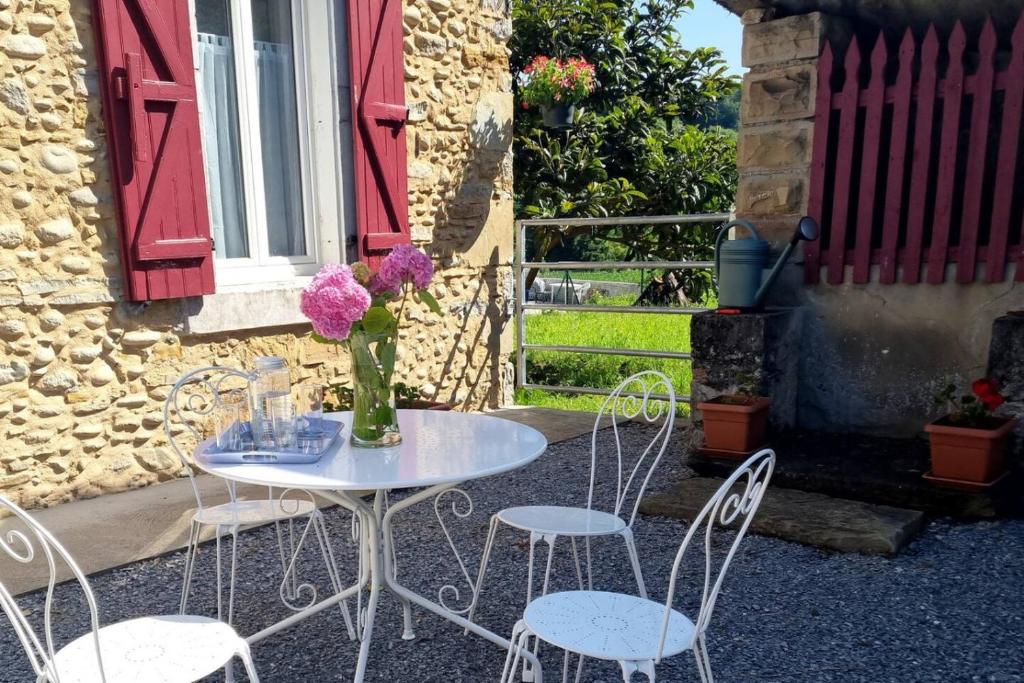a table and chairs with a vase of flowers on it at La petite Maison Rouge in Igon