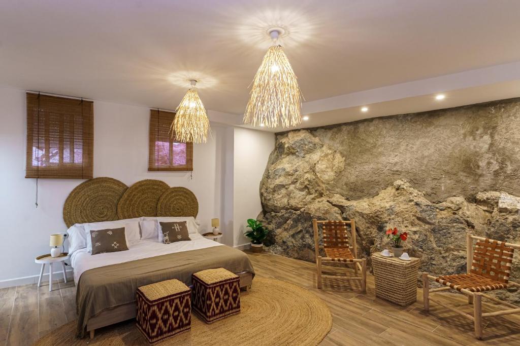 a bedroom with a bed and a rock wall at Raíces de Canillas Holiday Apartments in Canillas de Aceituno