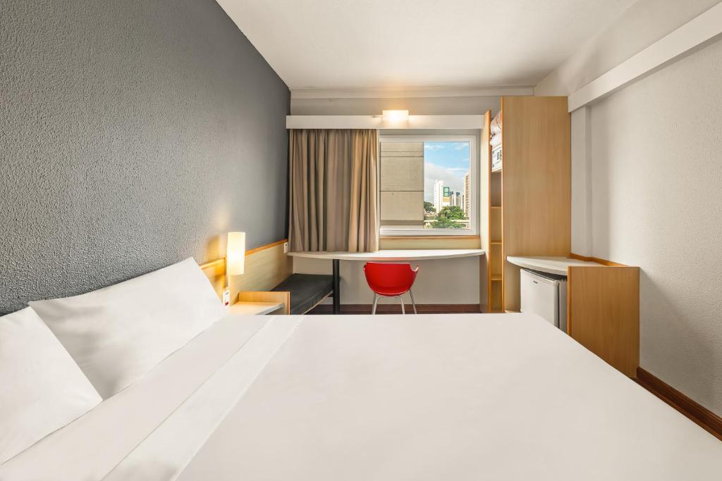a hotel room with a bed and a red chair at Slim Hotel Campinas in Campinas
