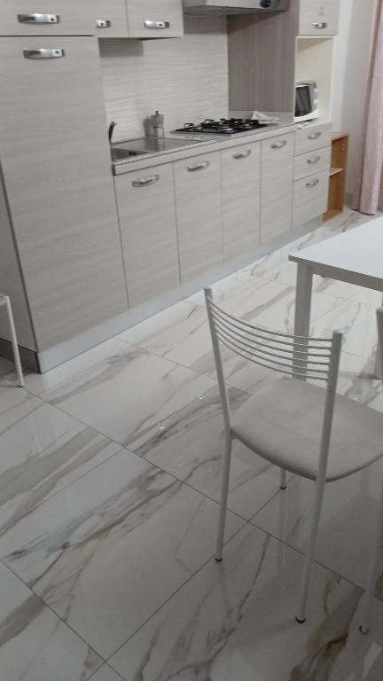 a white kitchen with a chair and a table at Appartamento Masha Como in Mozzate
