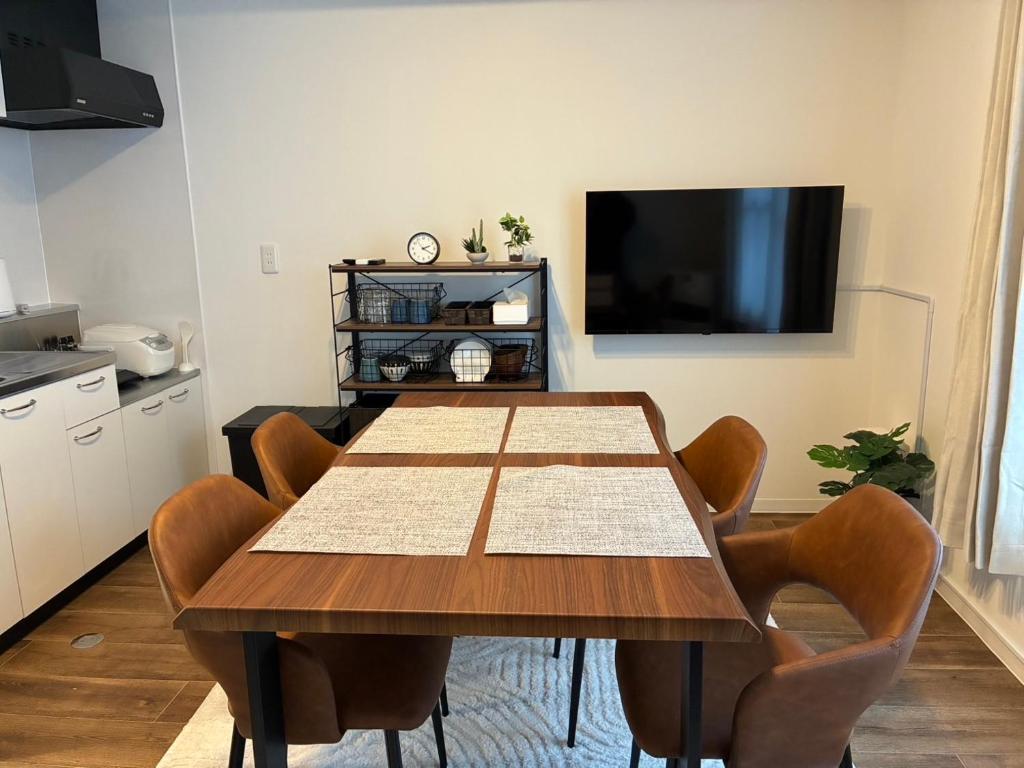 a dining room table with chairs and a flat screen tv at STAY Moiwayama in Sapporo