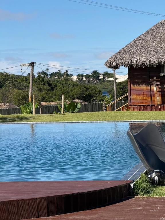 a swimming pool with a hut in the background at AREIA BRANCA Chalés in Santo Amaro