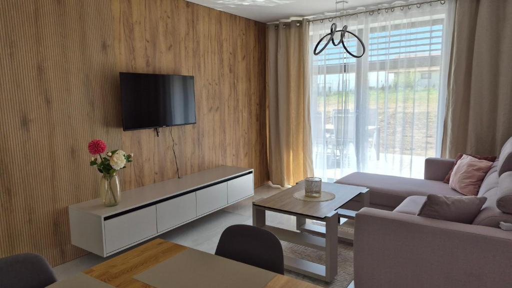 a living room with a couch and a tv on a wall at Apartman Bartimej 2 in Bobrów