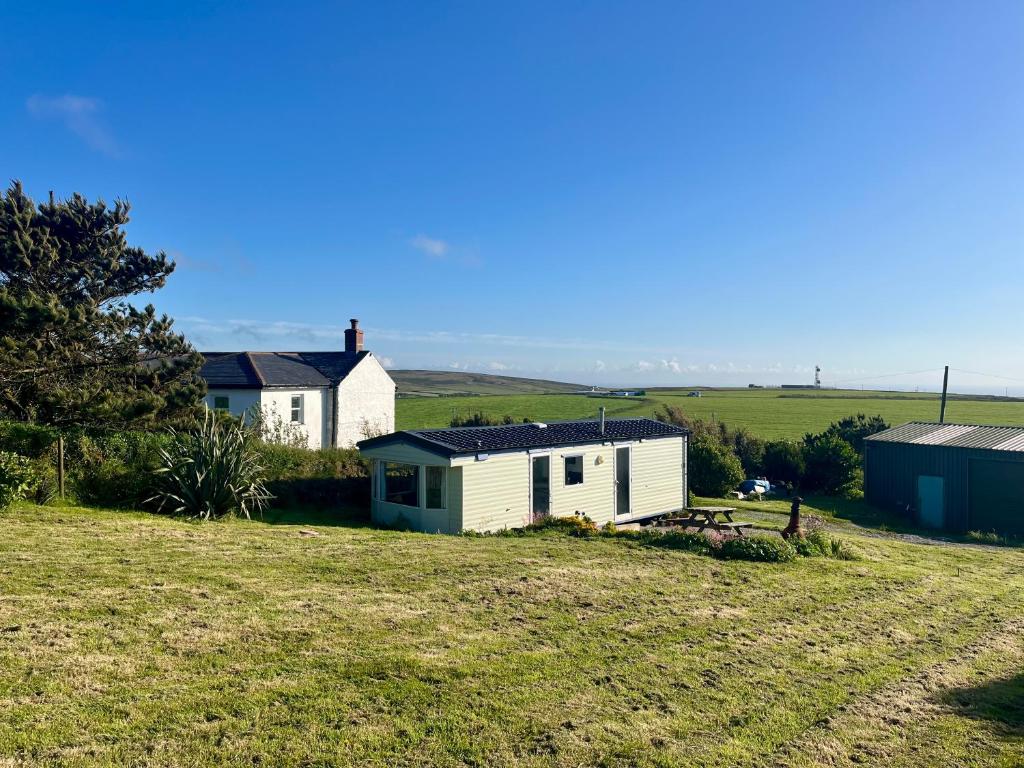 a house on a grassy hill next to a house at Carn Kenidjack View Caravan, space, peace and tranquillity in Penzance