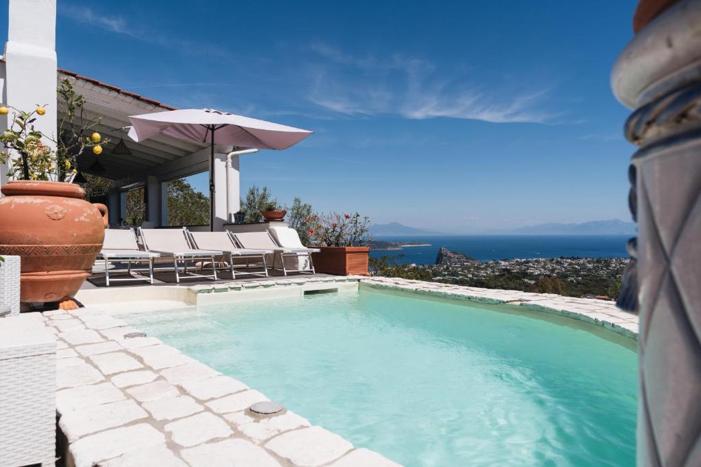 a swimming pool with chairs and an umbrella at Relais Villa Ettore in Barano d'Ischia