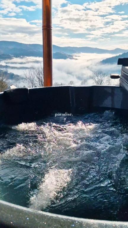 a hot tub filled with water with a view of clouds at Cabana Magia Apusenilor in Arada