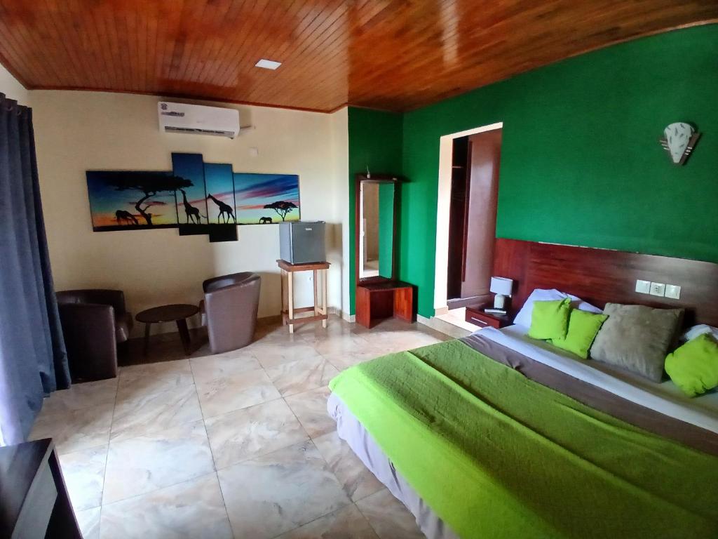 a bedroom with a green wall with a bed and a table at Hotel Palm Rock Beach in San-Pédro