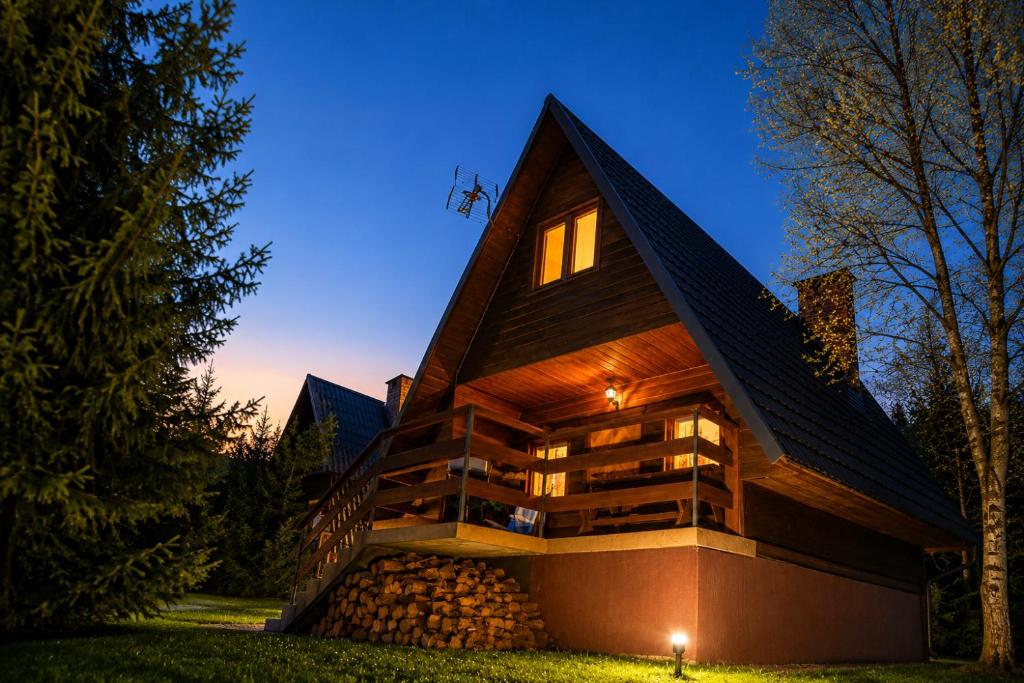 a house with a gambrel roof at night at Domki Bieszczady Siedlisko Harenda in Czarna