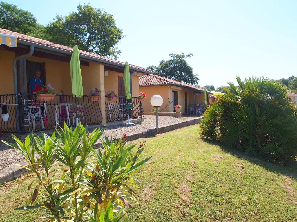 a person standing outside of a house with umbrellas at Palmiers 1 in Barbotan-les-Thermes