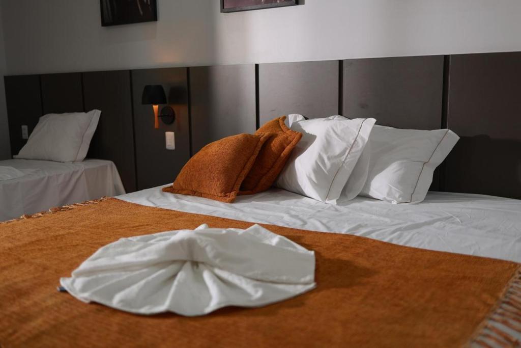 a bed with white sheets and towels on it at Pousada Villa Ricca Park in Niquelândia