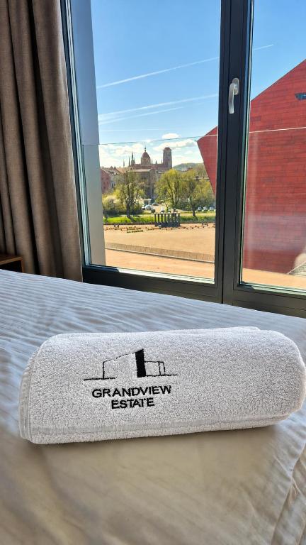 a white towel on a bed in front of a window at Brabank Penthouse Old Town View, Sauna & Parking by Grandviewestate in Gdańsk