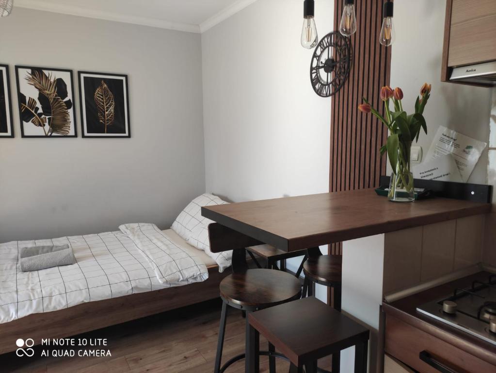 a small room with a bed and a table with a kitchen at Pokoje Gościnne Leśna 33 in Sława