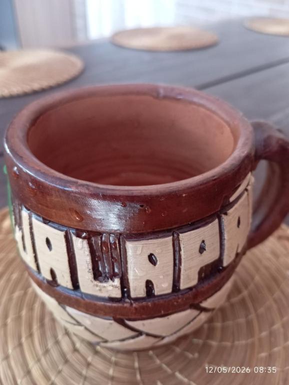 a brown and white coffee cup sitting on a table at Pousada Jalapão Rosa do deserto in Mateiros
