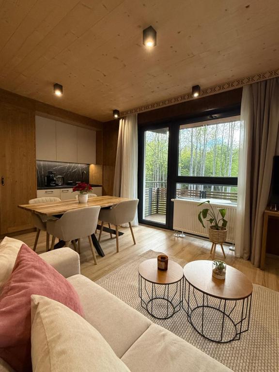 a living room with a couch and tables and a kitchen at Apartmán Forest, Tatranská Štrba in Tatranska Strba