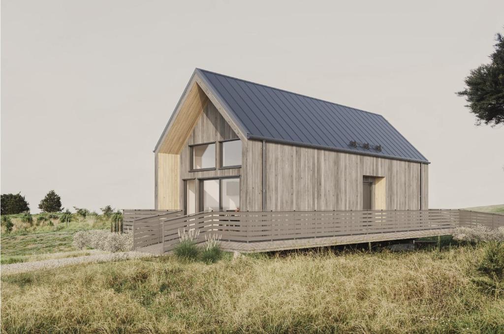 a wooden house with a black roof on a field at Sandvikens Strandby in Katthammarsvik