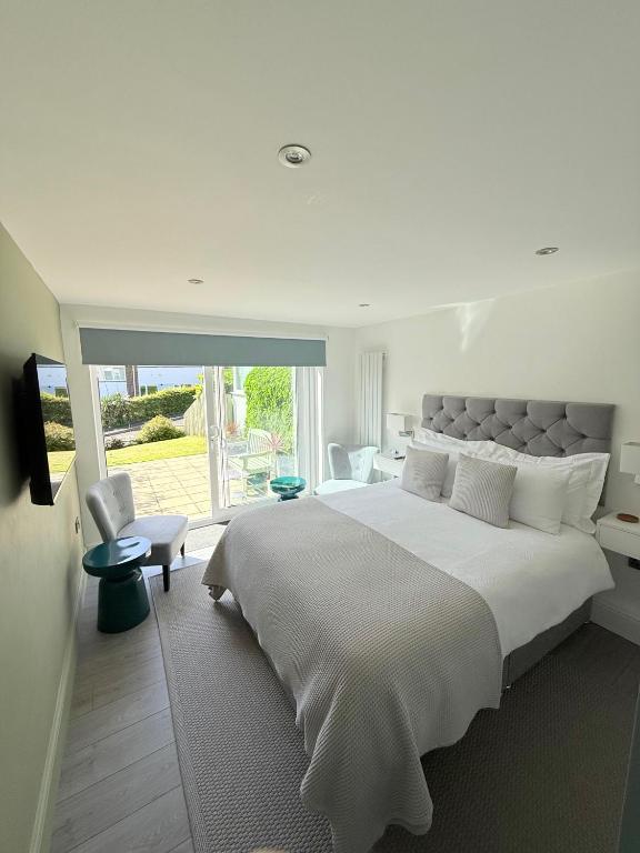 a white bedroom with a large bed and a window at Tŷ Treflan in Aberdyfi