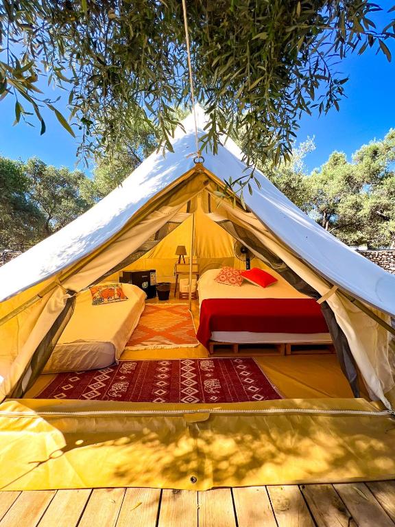 a yellow tent with two beds and a wooden floor at Ruina Glamping in Mezgit