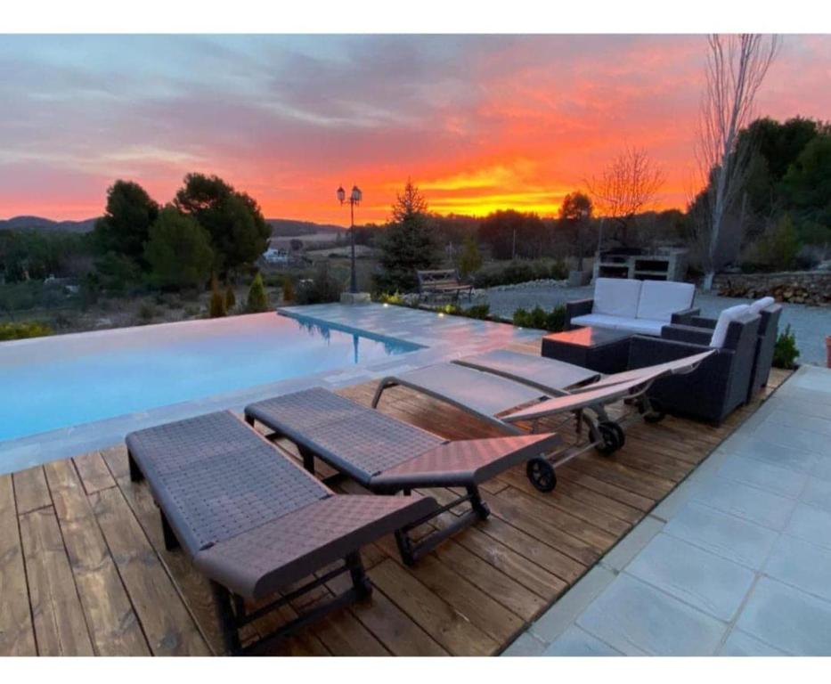a pool with chairs and a sunset in the background at Quinta de Argos in Cehegín