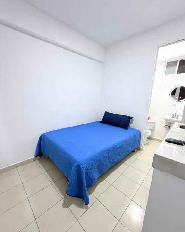 a bedroom with a blue bed in a white room at Hotel Posada Centro Atlacomulco Cuarto Barra in Atlacomulco de Fabela