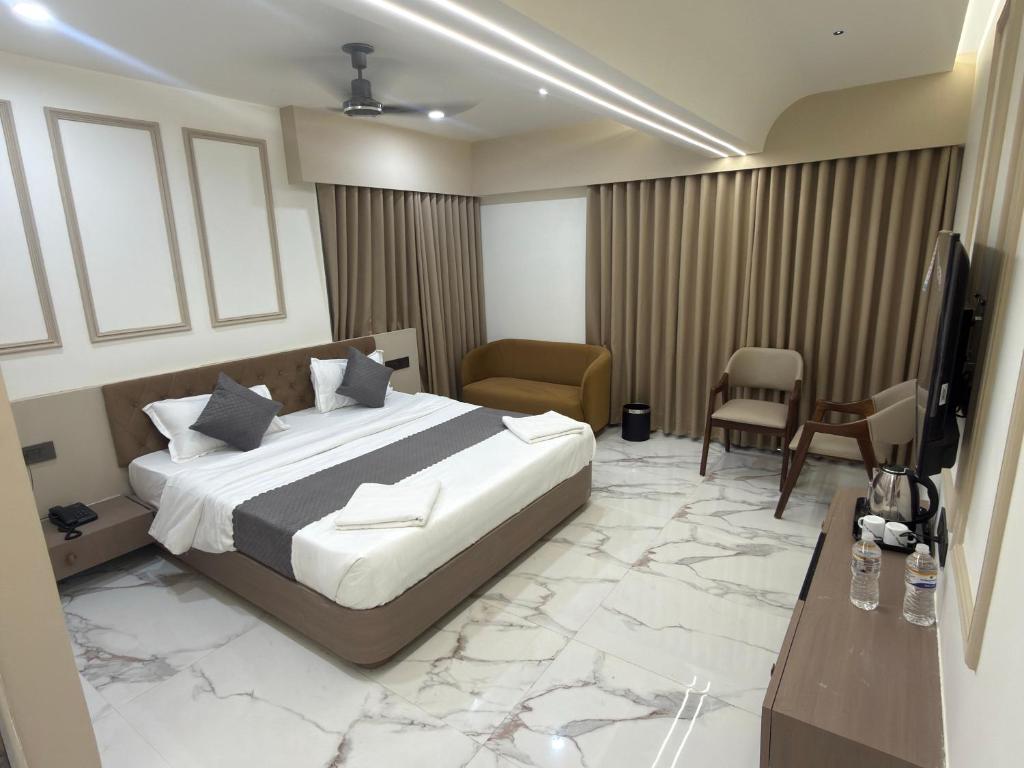 a bedroom with a bed and a television and a desk at Hotel Yagnik Inn in Rajkot