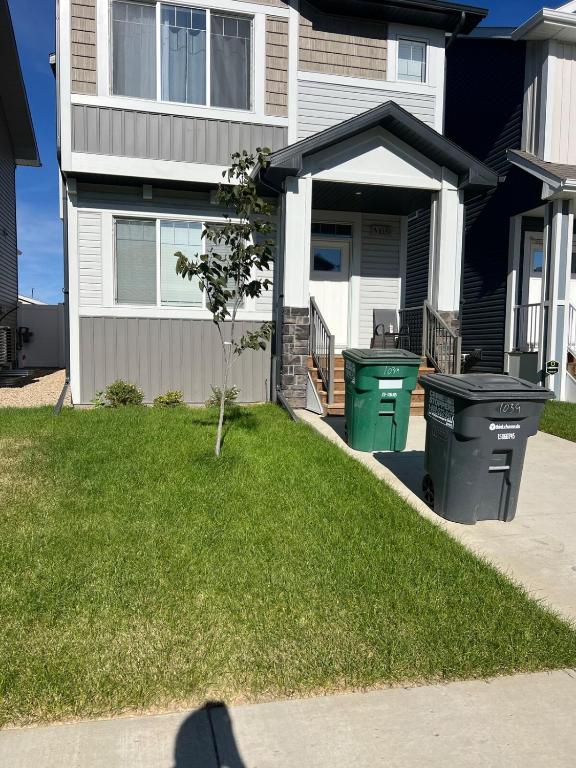 a house with two trash cans in a yard at Restful Basement Suite Hideaway in Saskatoon