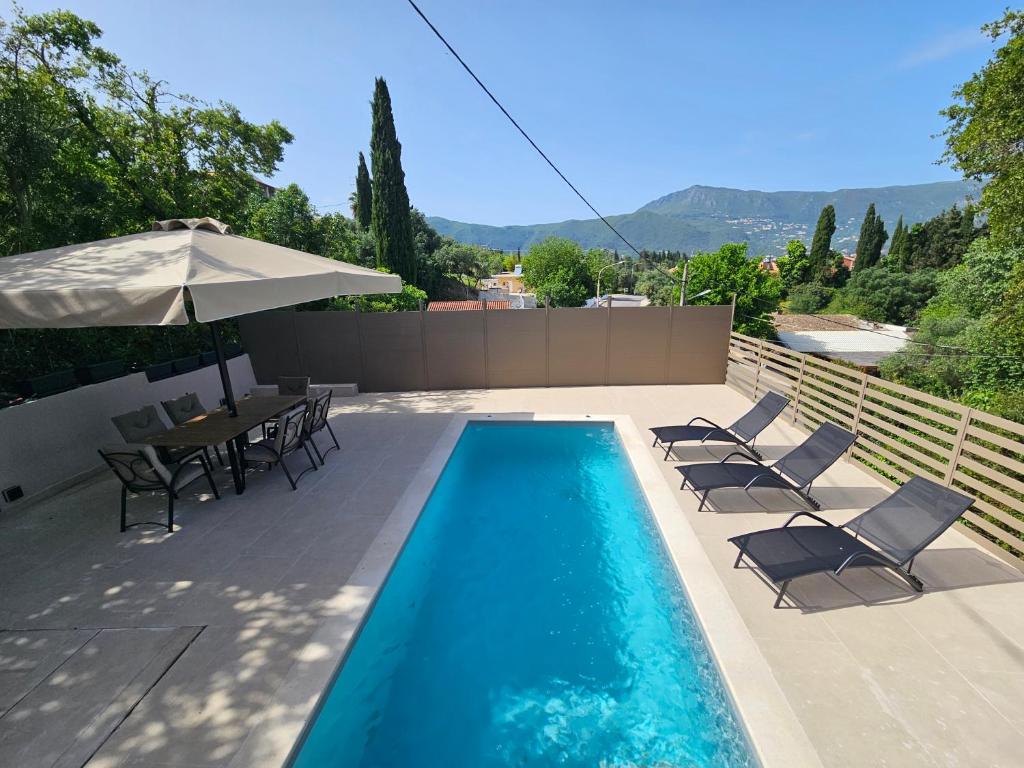 ein Schwimmbecken mit Stühlen, einem Tisch und einem Sonnenschirm in der Unterkunft Casa Sofia in Dassia